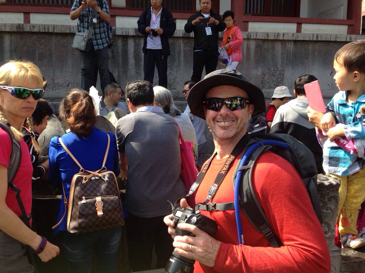 Traveler holding a camera among visitors at a historic site