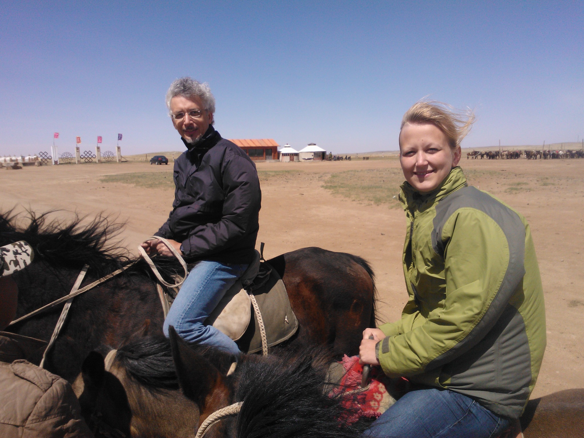 Two travelers riding horses across open grasslands