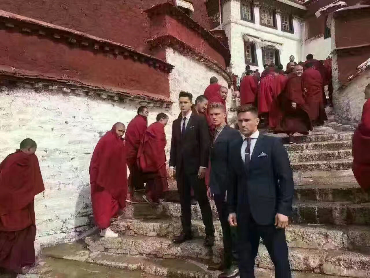 Travelers standing on monastery steps beside monks