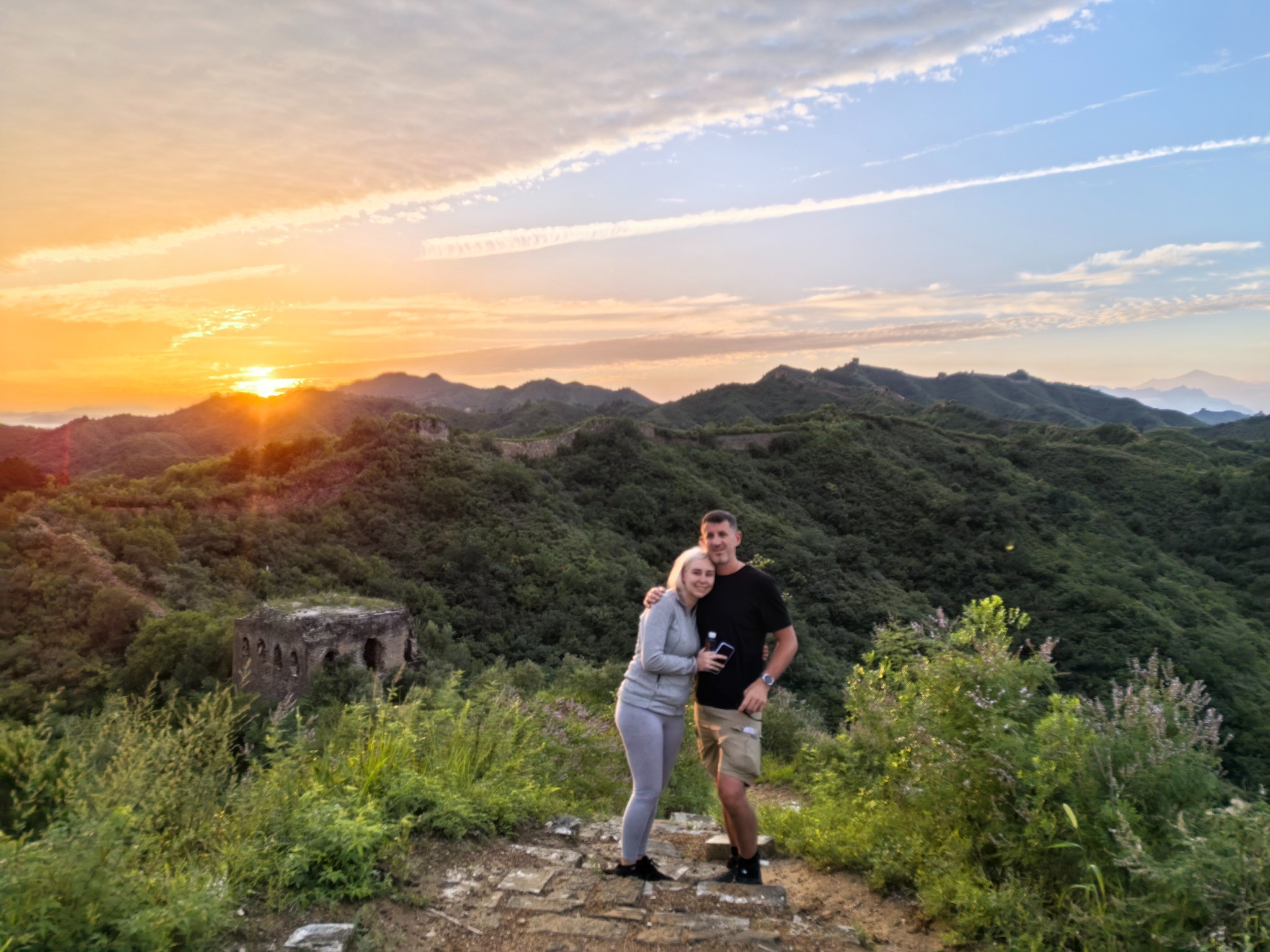 Two travelers posing on the Great Wall at sunset