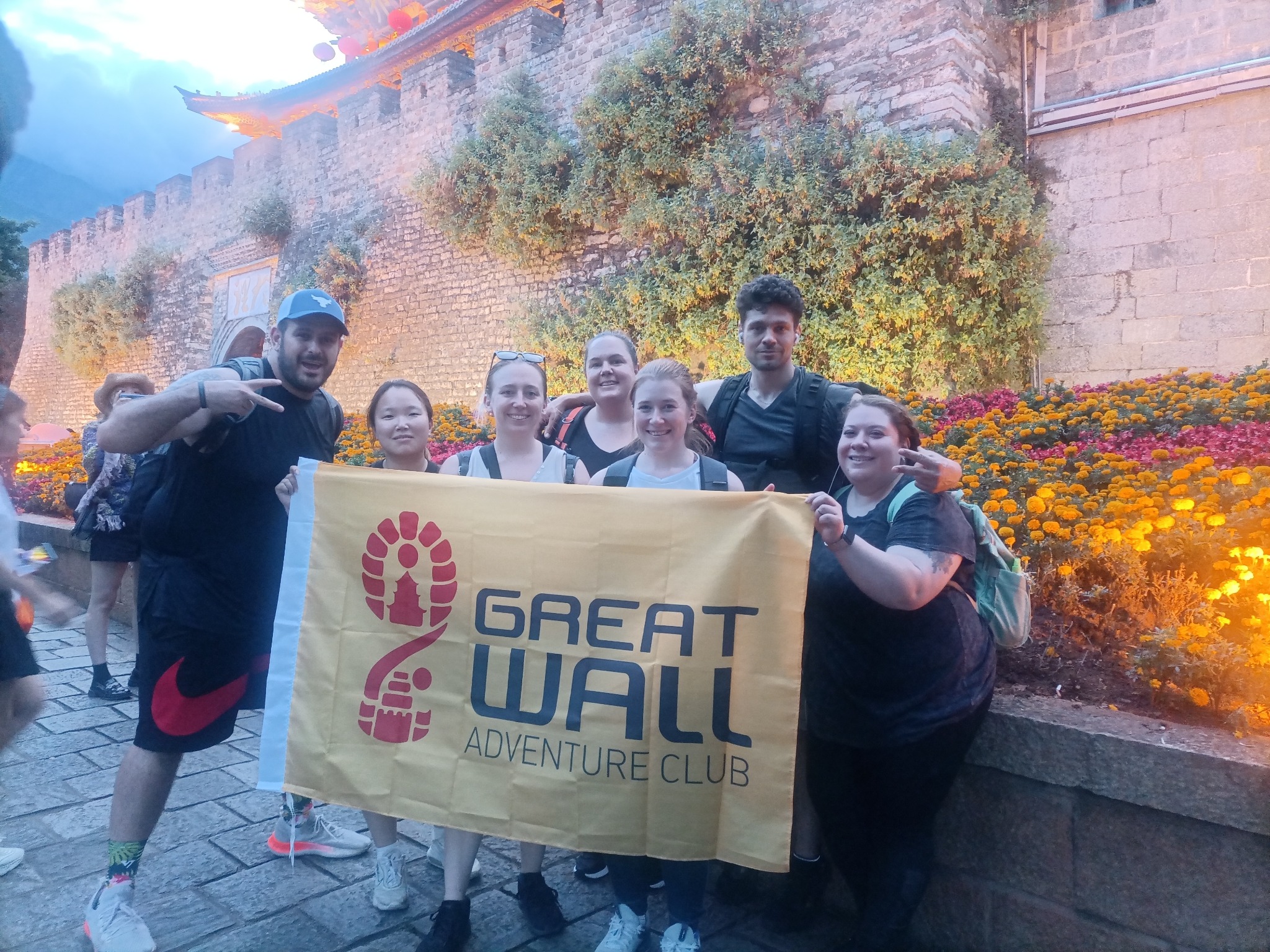 Travelers holding a Great Wall Adventure Club banner in a historic courtyard