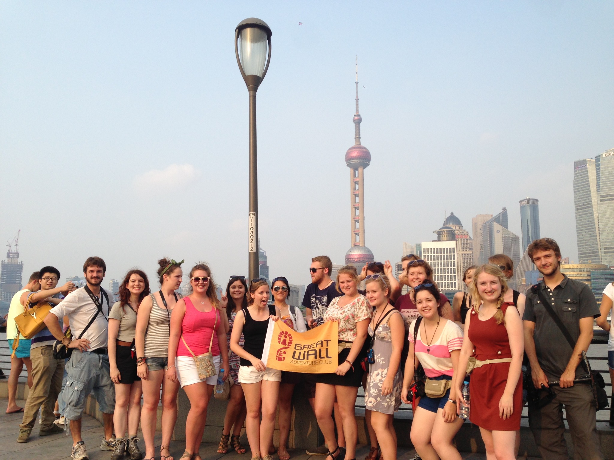Traveler group holding a Great Wall Adventure Club banner on the Shanghai waterfront
