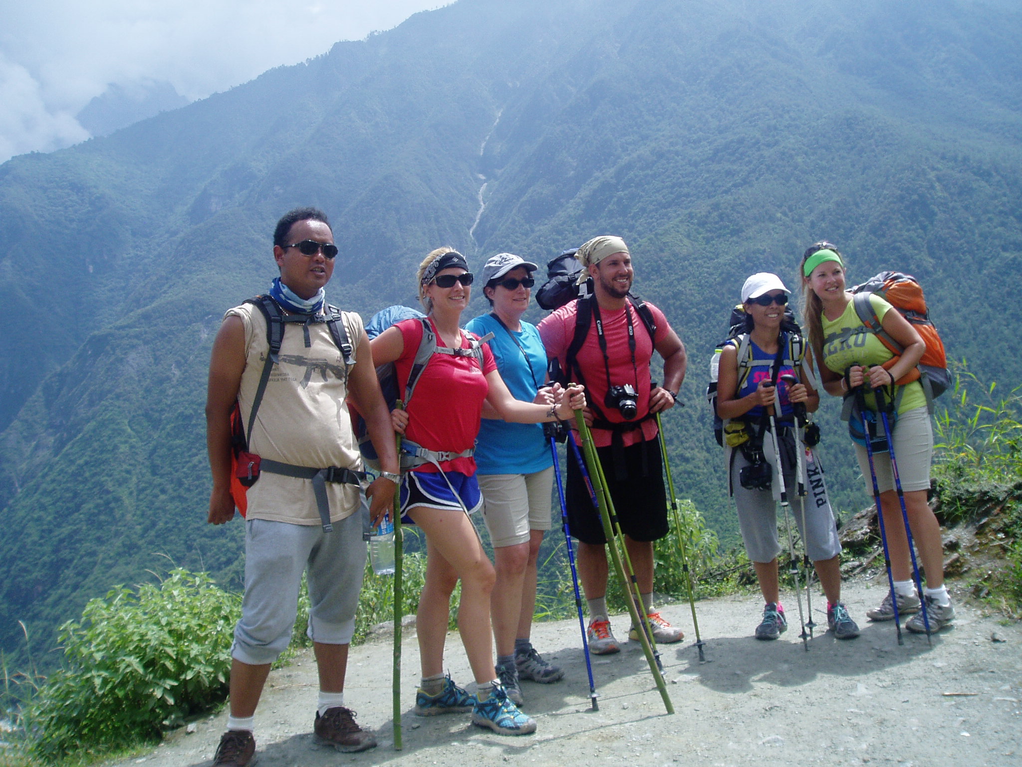 Six hikers with backpacks and trekking poles on a mountain trail